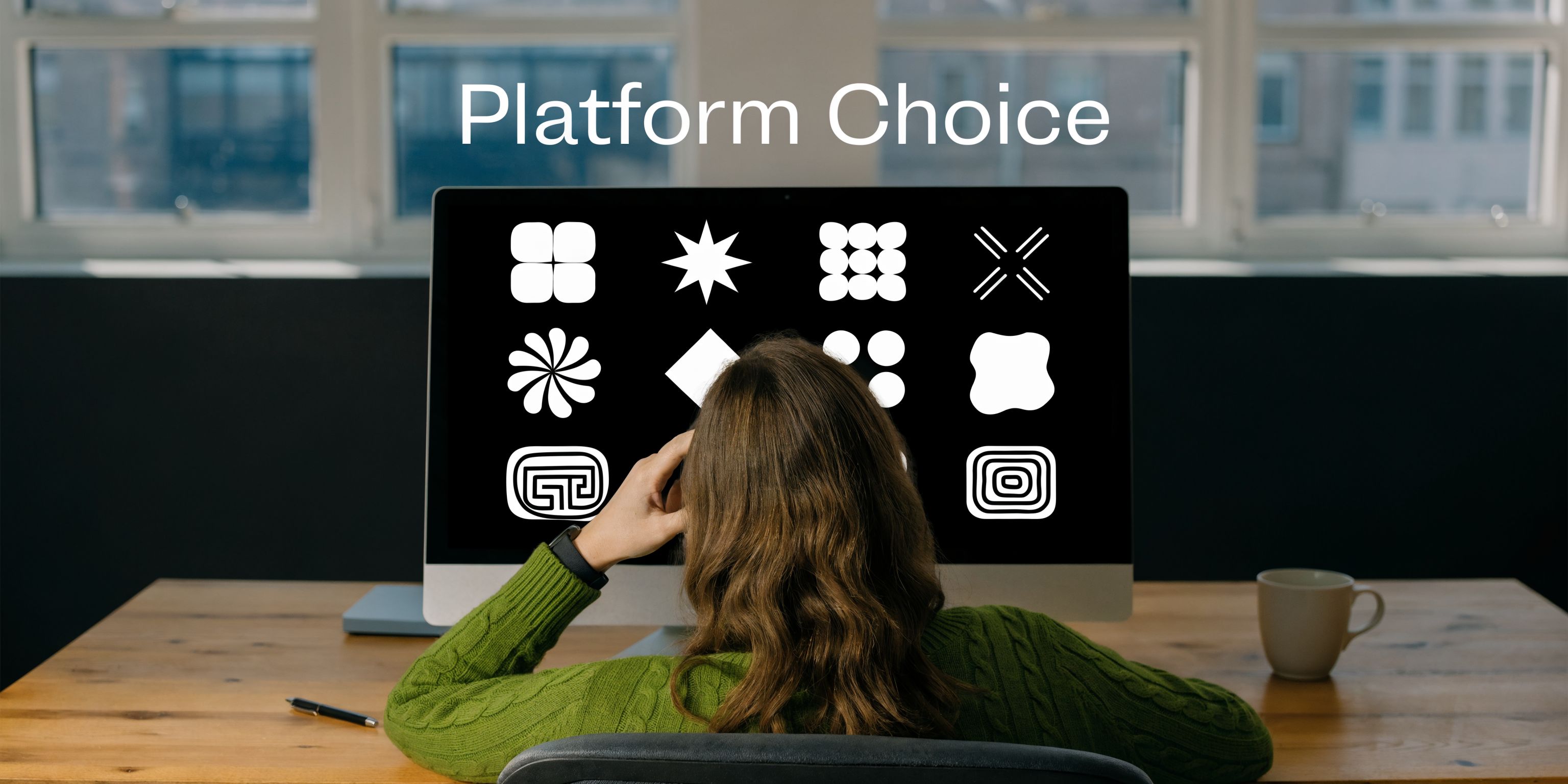 A person sitting at a desk looking at a computer screen displaying various abstract icon choices.