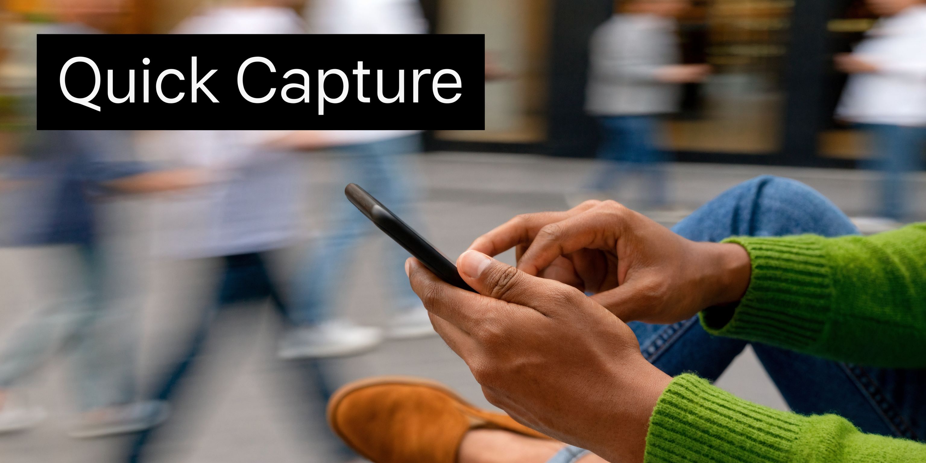 A person using their smartphone while sitting in a busy outdoor public area with motion blur.